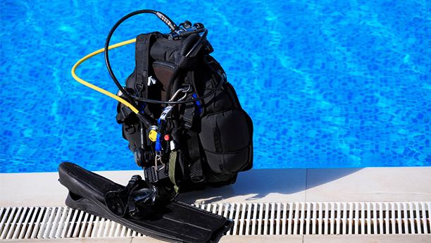 a scuba gear bag sitting next to a swimming pool.