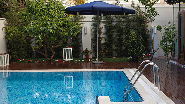 a resurfaced pool with a blue umbrella and a wooden deck.